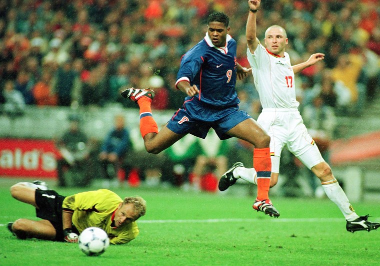Patrick Kluivert springt over keeper Filip De Wilde heen tijdens de WK-wedstrijd Nederland-België in 1998. Dat duel in Parijs (0-0) leidde tot de revolutie in de Belgische voetbalopleiding. Rechts Mike Verstraeten.
