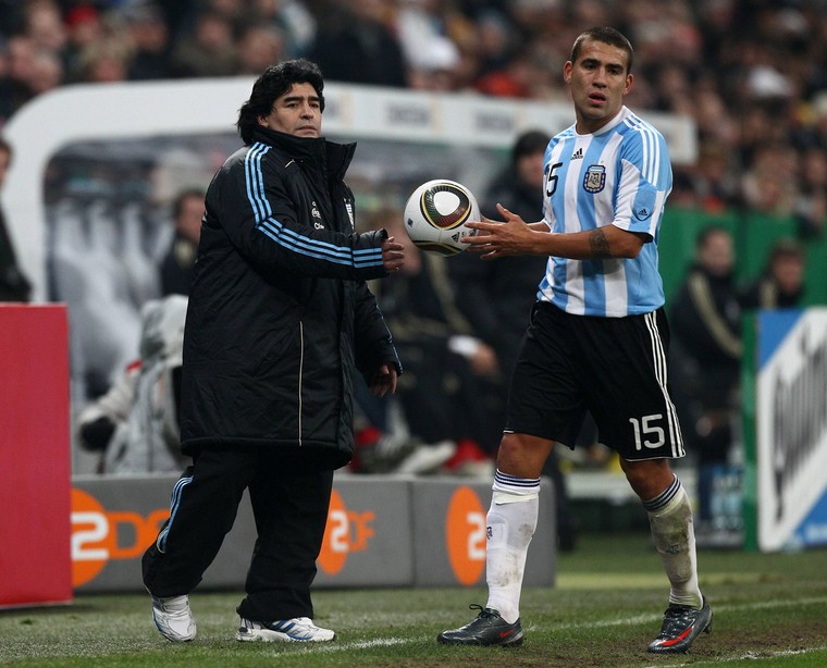 Diego Armando Maradona overhandigt gelegenheidsrechtsback Nicolás Otamendi de bal tijdens het WK 2010.