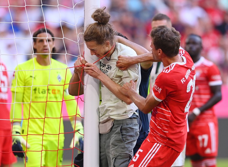 Tijdens de wedstrijd ketenden twee klimaatactivisten zich vast aan de doelpalen, wat Thomas Müller nog probeerde te voorkomen.