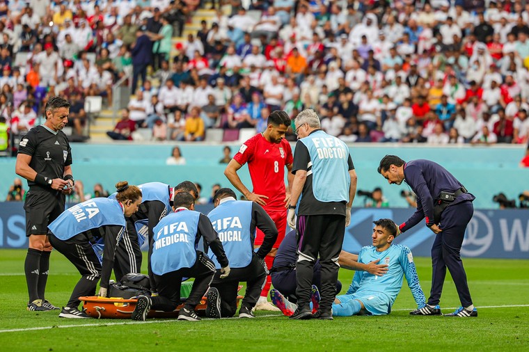 De Iraanse keeper Alireza Beiranvand zit aangeslagen op het veld na een harde botsing.