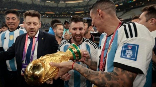 Ángel Di María laat aan Lionel Messi zien dat de wereldbeker waarmee hij rondliep in Qatar een replica is.