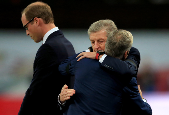 Roy Hodgson (rechts) omhelst zijn collega Didier Deschamps. Op de achtergrond rouwt de Engelse prins William.