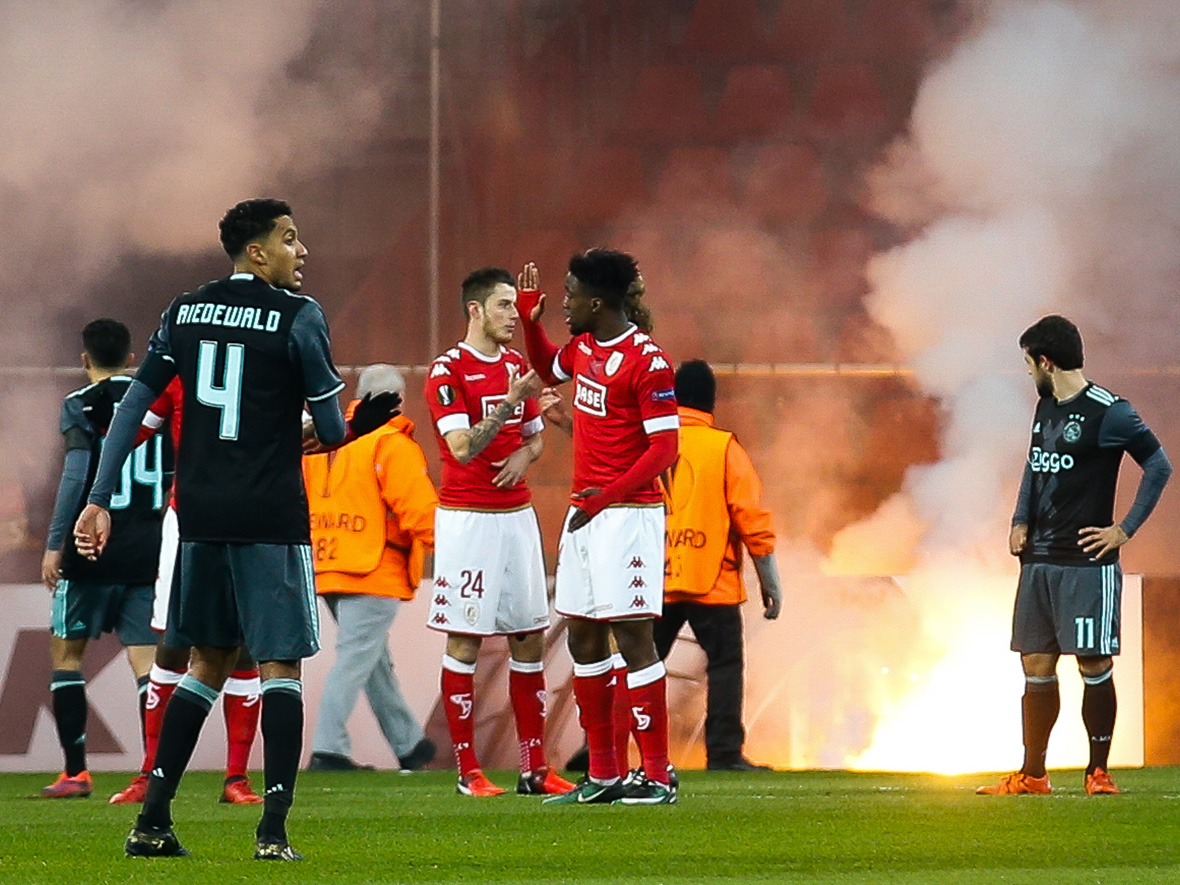 De Ajax-fans laten zich van hun slechtste kant zien en gooien vuurwerk op het veld en in vakken met Belgische supporters.