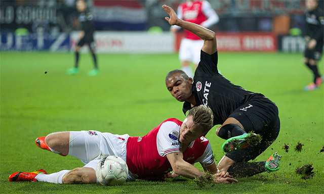 Mattias Johansson wordt in de wedstrijd tegen Heracles Almelo onderuit gehaald door Mikhail Rosheuvel.