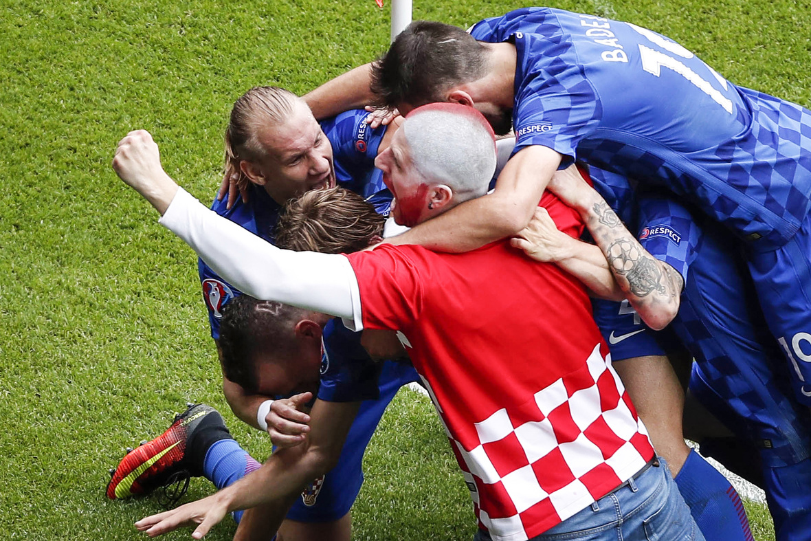 Een Kroatische fan is uitzinnig van vreugde na de openingstreffer van Luka Modric tegen Turkije en besluit het feestje mee te vieren. Milan Badelj vindt het prima en omhelst hem.