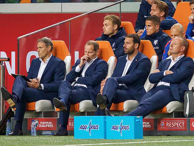 Waar voor de wedstrijd vooral gespannen gezichten te zien waren bij de nieuwe technische staf van het Nederlands elftal, druipt nu het chagrijn ervan af. Blind en consorten zien de bui al hangen. 1-0 achter en het spel is, op zijn zachtst gezegd, niet best.