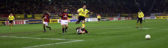 Yannis Anastasiou, toen spits, nu trainer. Hier in duel met AC Milan tijdens de thuiswedstrijd.