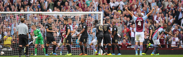 Aston Villa-aanvoerder Ron Vlaar heft zijn armen de lucht in, nadat Leandro Bacuna (rechts, juichend) tegen Manchester City heeft gescoord uit een vrije trap.