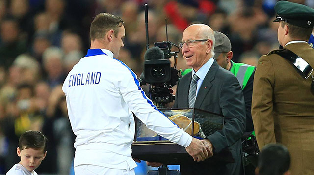 Sir Bobby Charlton geeft Wayne Rooney een &#039;gouden cap&#039; voor zijn honderdste interland.