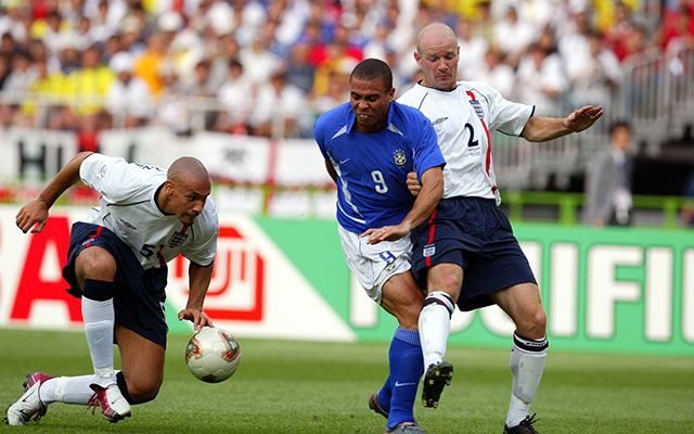 Rio Ferdinand, hier op het WK 2002 samen met rechtsback Danny Mills (nummer 2) in duel met de Braziliaanse spits Ronaldo, was jarenlang de duurste verdediger aller tijden.