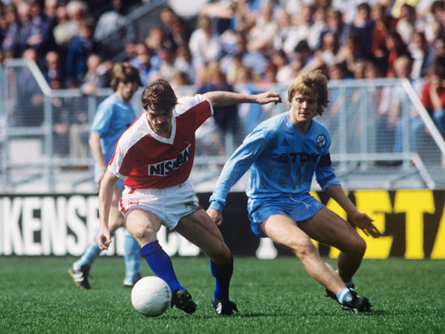 Jan Wouters, momenteel trainer van FC Utrecht, gaat in zijn jonge jaren de strijd aan met Sören Lerby. Op de achtergrond kijkt Jesper Olsen gespannen toe.