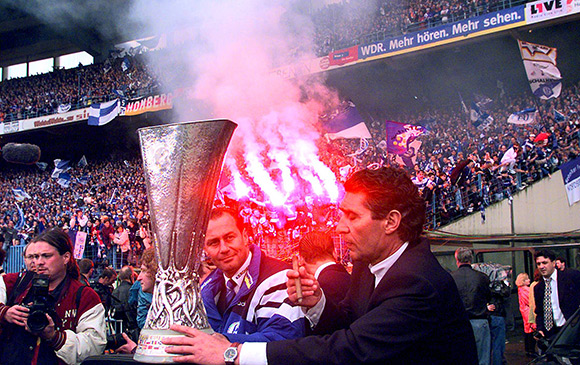 Manager Rudi Assauer (rechts) steekt een dikke sigaar op als trainer Huub Stevens hem en Schalke 04 in 1997 de UEFA Cup bezorgd heeft. Stevens werd in 1999 uitgeroepen tot Trainer van de Eeuw.