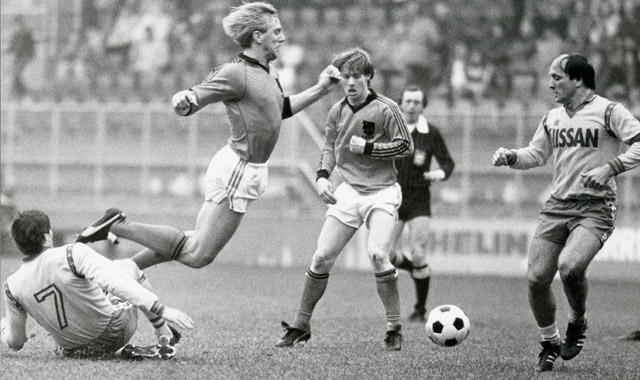 Onder toeziend oog van Dick Advocaat haalt Jan Wouters in seizoen 1982/&#039;83 zijn ploeggenoot Willy Carbo onderuit in een oefenduel tussen FC Utrecht en Jong Oranje. Behalve Advocaat is ook Mario Been, tegenwoordig trainer van RC Genk, toeschouwer.