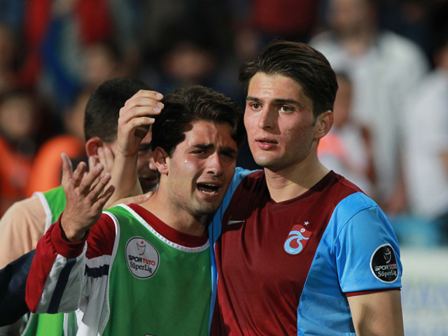 Een wisselspeler van Trabzonspor reageert emotioneel de misdragingen van de supporters, die ook stoeltjes het veld op gooiden.