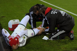 Arjen Robben verbijt de pijn als hij wordt behandeld aan zijn rechterknie.