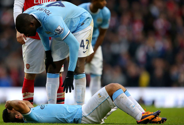 Sergio Agüero ligt geblesseerd op de grond tijdens het duel met Arsenal. Yaya Touré bekommert zich om zijn teamgenoot. 